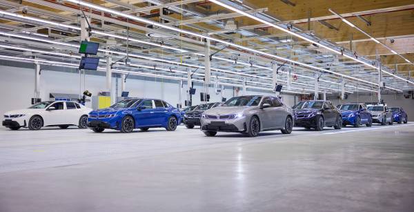 Plusieurs BMW i3 blanches, bleues et grises stationnées dans le hall de remise de l'usine BMW de Munich avant contrôle final