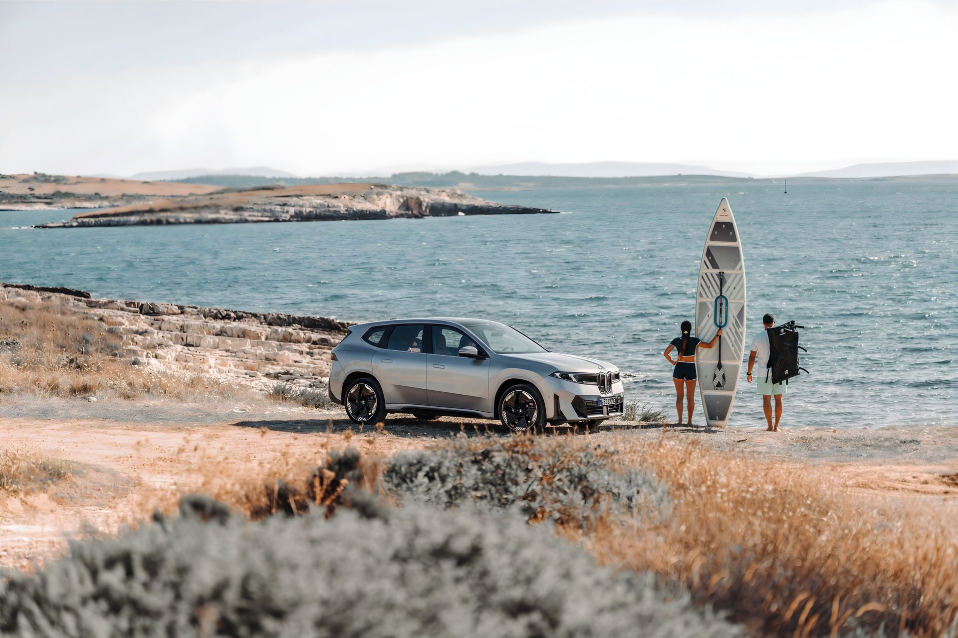 BMW iX3 stationnée sur une aire de repos en été, coffre ouvert pour les vacances