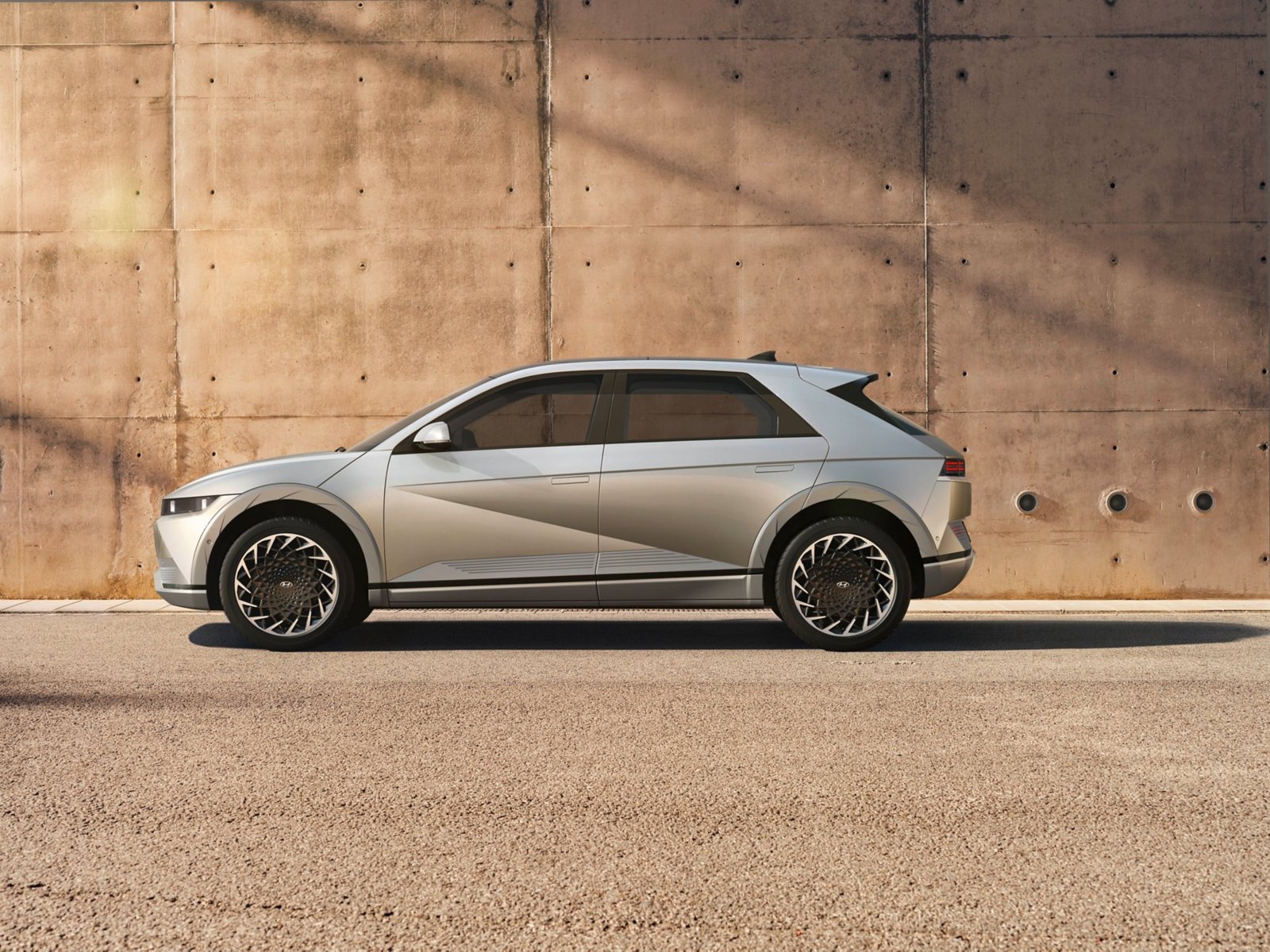 Hyundai IONIQ 5 gris clair vue de profil devant un mur en béton