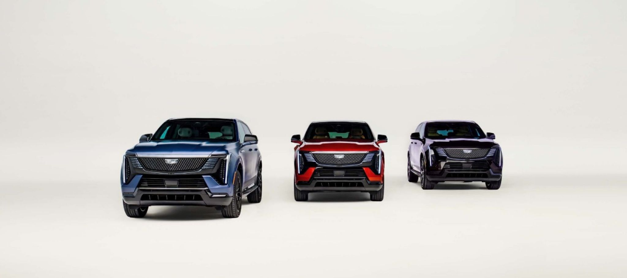 Trois Cadillac Escalade IQ Curated 2027 de face dans des teintes personnalisées bleue, rouge et violette