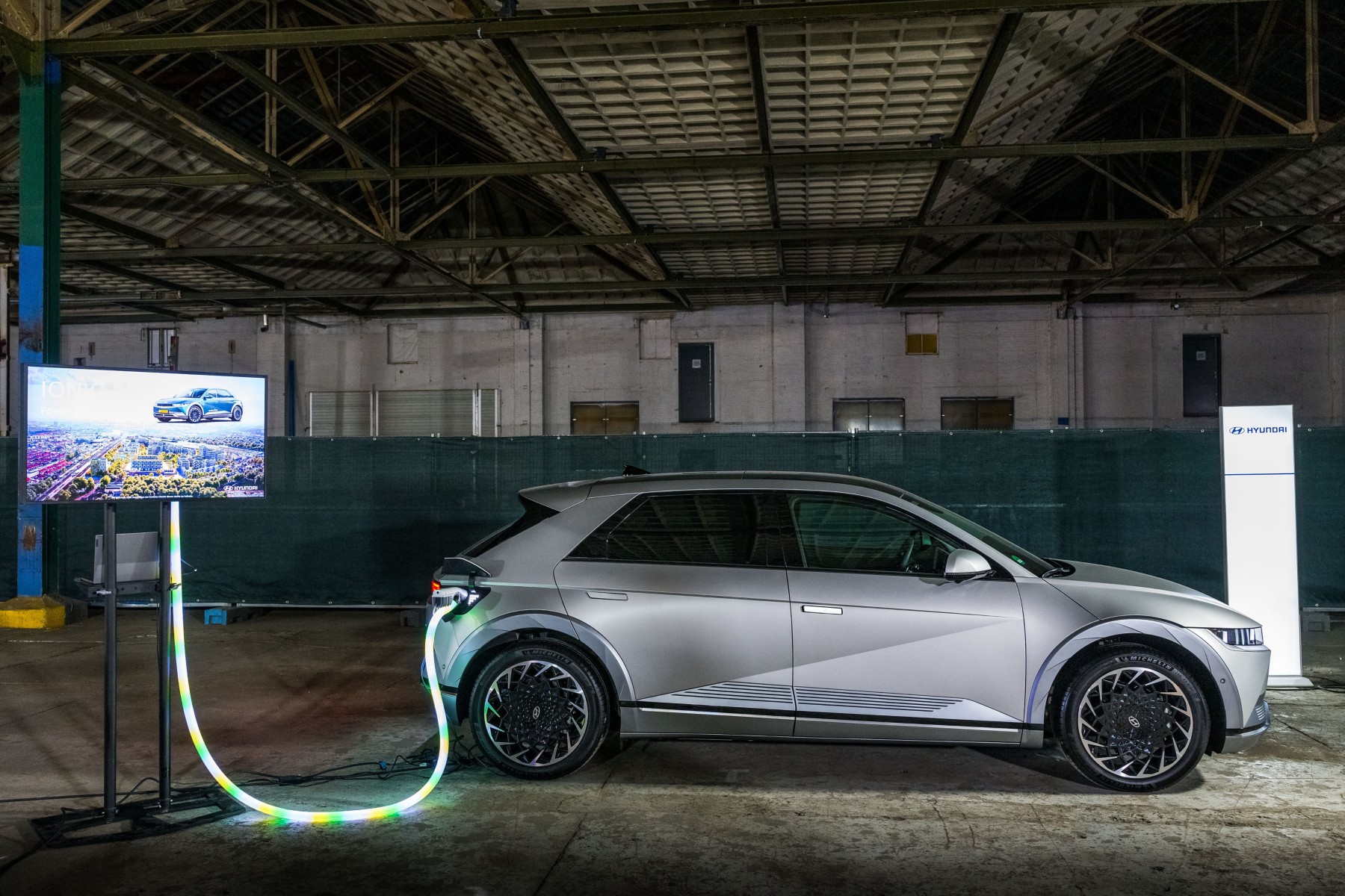 Hyundai IONIQ 5 grise branchée à une borne de recharge, câble lumineux au sol, lors du lancement des services énergétiques du groupe