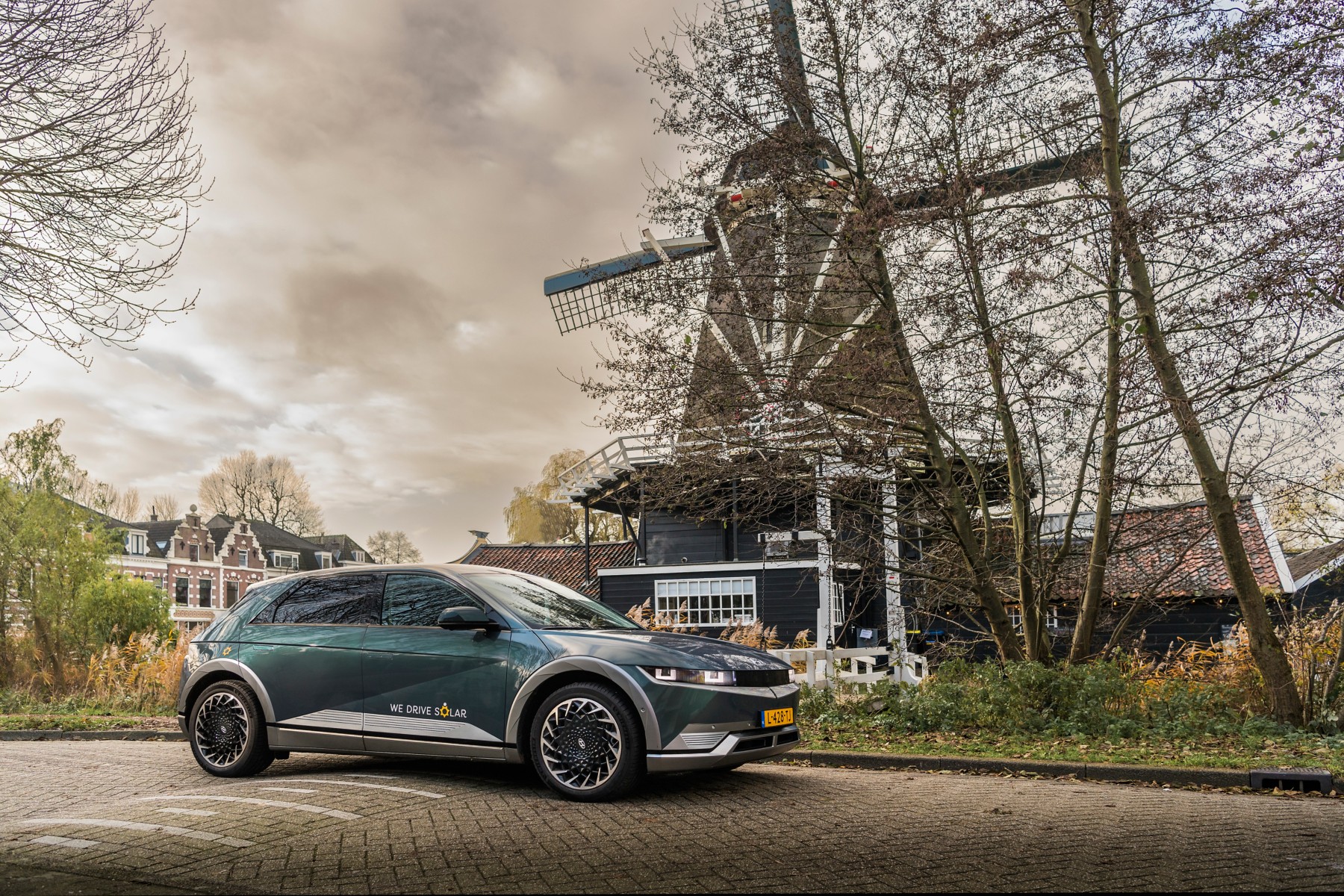Hyundai IONIQ 5 aux couleurs du projet We Drive Solar stationnée devant un moulin à Utrecht, aux Pays-Bas