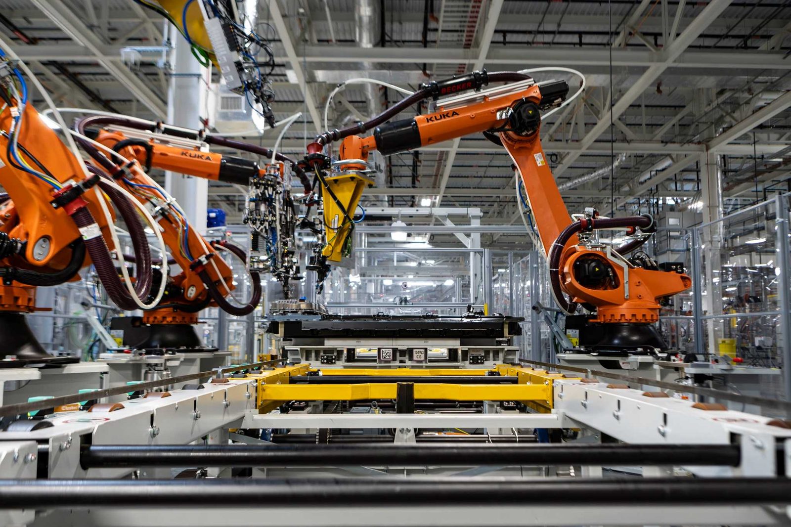 Robots KUKA orange assemblant un plancher de batterie haute tension Gen6 sur la ligne de l'usine BMW de Woodruff