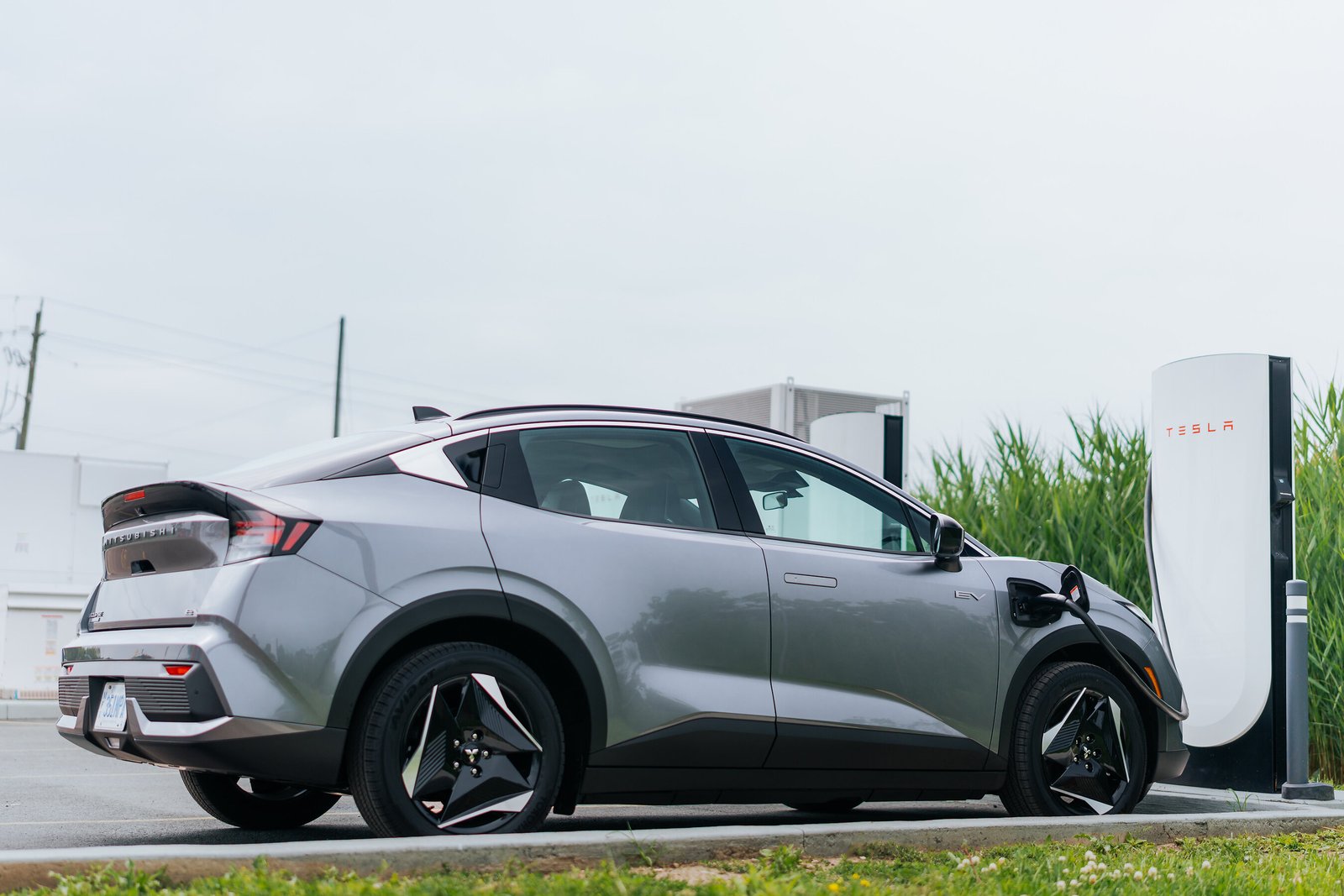 Vue arrière du Mitsubishi Eclipse Sportback EV 2027 en recharge rapide sur une station Tesla Supercharger