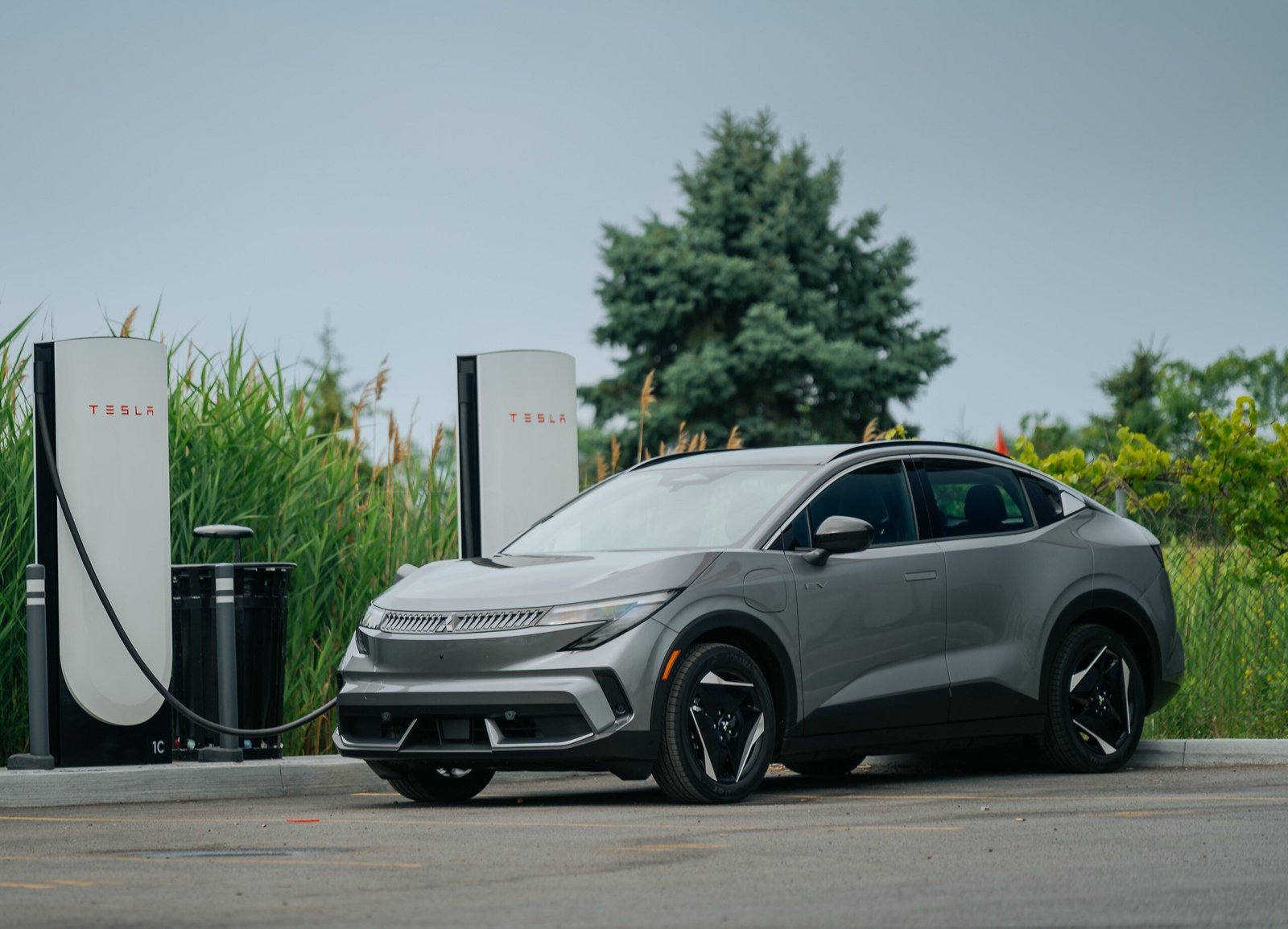 Mitsubishi Eclipse Sportback EV 2027 branchée de face à une borne Tesla Supercharger via sa prise NACS