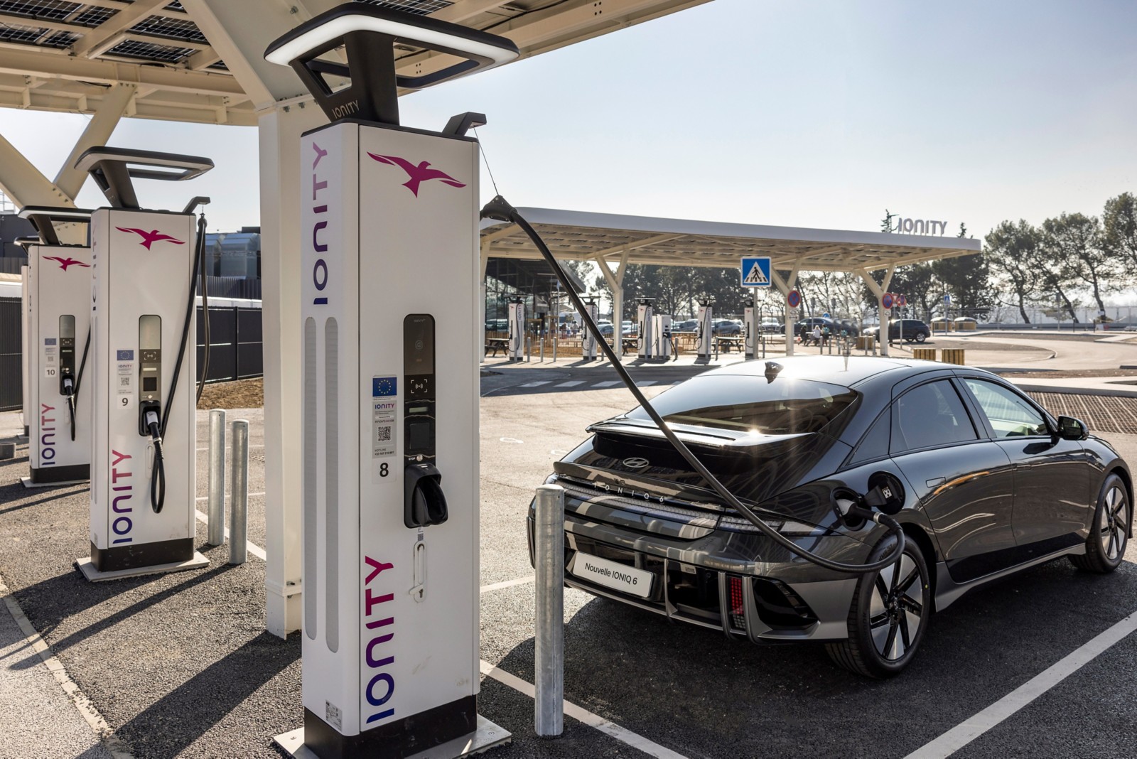 Hyundai IONIQ 6 grise branchée à une borne de recharge rapide extérieure sous un abri photovoltaïque