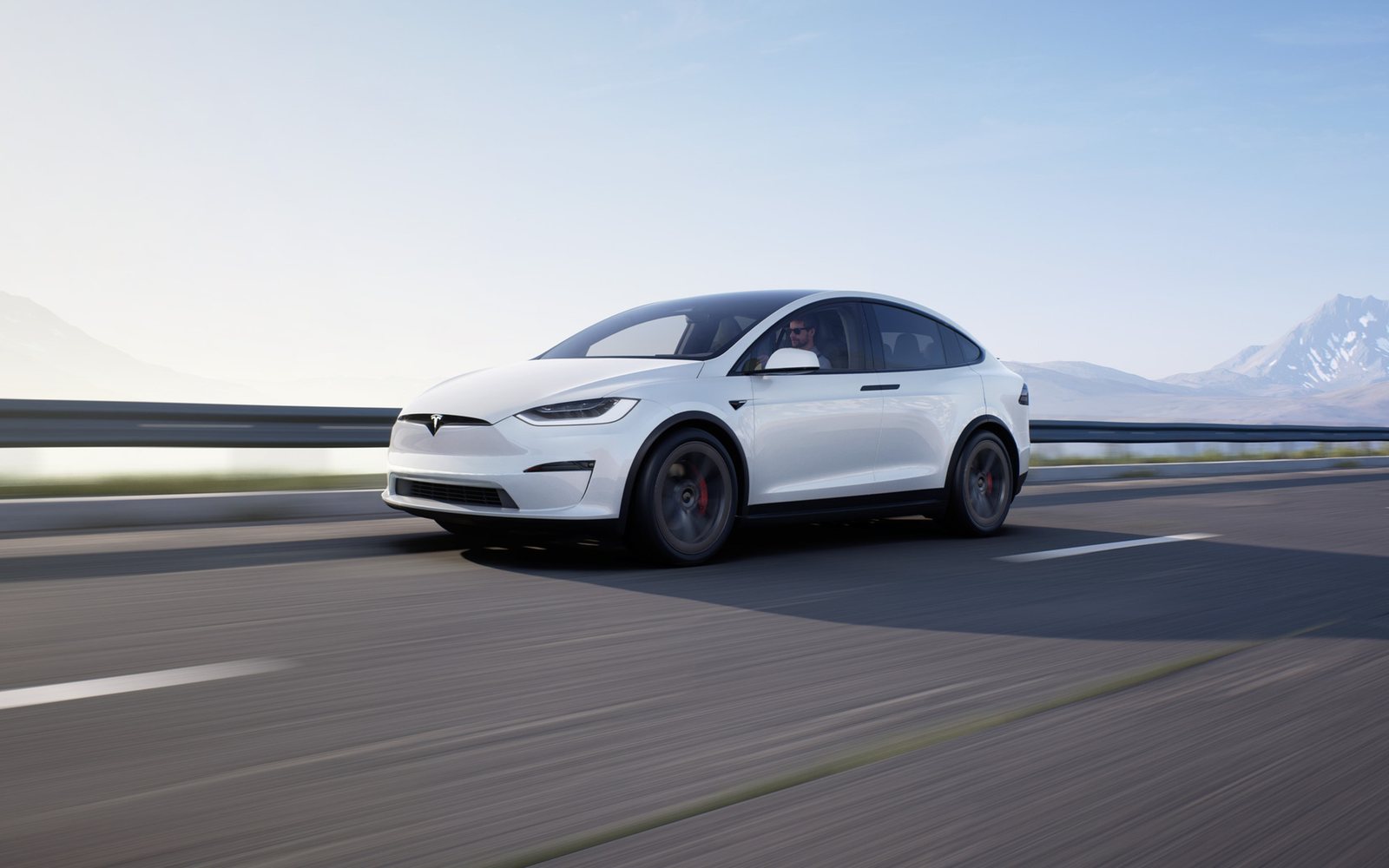Tesla Model X blanche roulant sur une route dégagée par temps ensoleillé