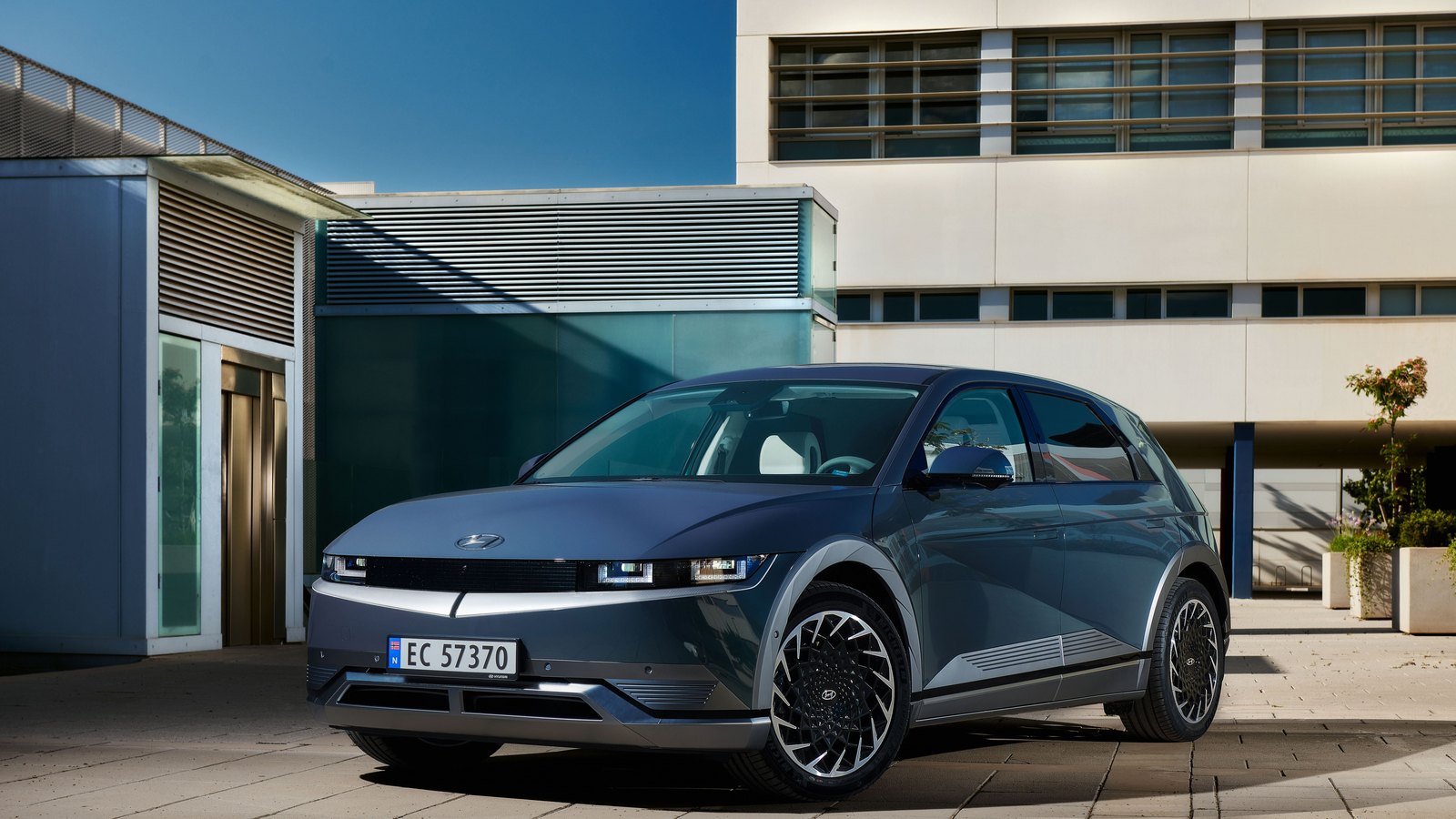 Hyundai IONIQ 5 grise vue de trois quarts avant devant un bâtiment moderne vitré