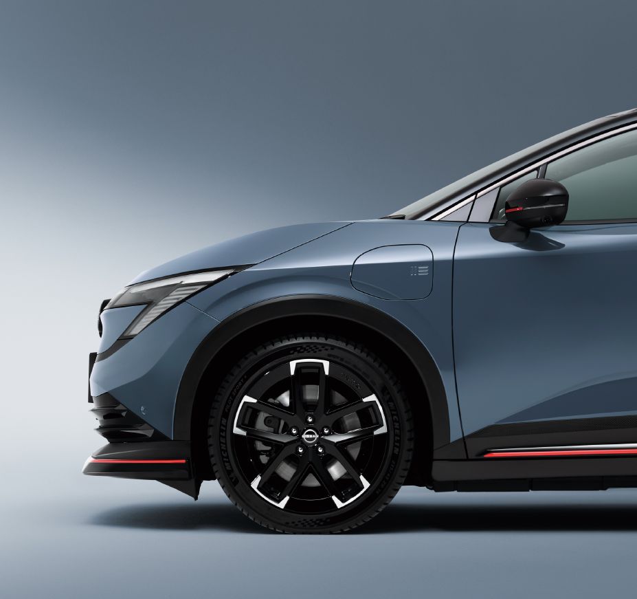 Gros plan avant droit de la Nissan Leaf NISMO gris Stealth : jante alliage noire 19 pouces et bas de caisse à liseré rouge NISMO