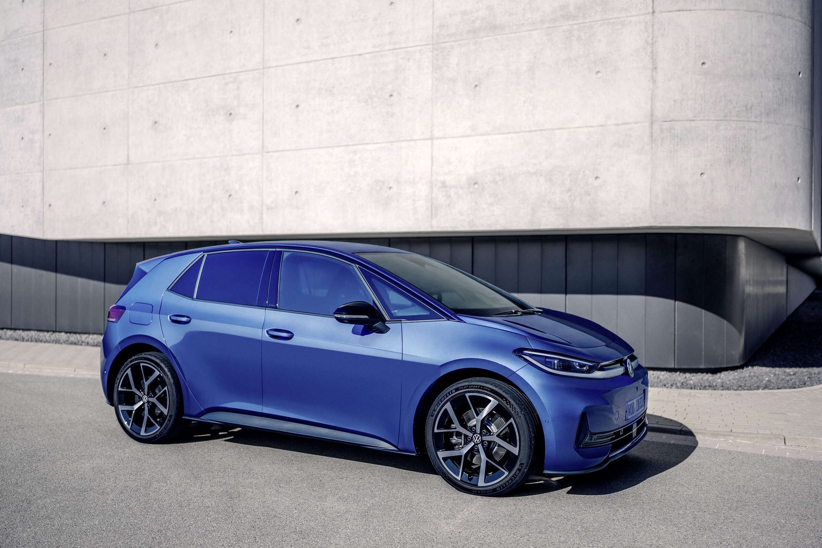 Volkswagen ID.3 Neo bleue à l'arrêt devant un mur en béton, vue de trois quarts avant