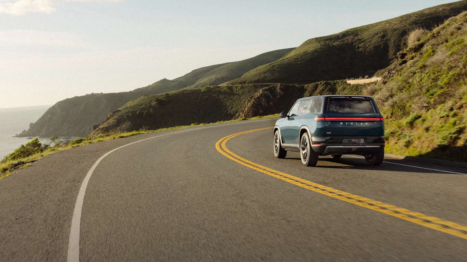 Rivian R2 électrique de couleur bleue sur une route côtière