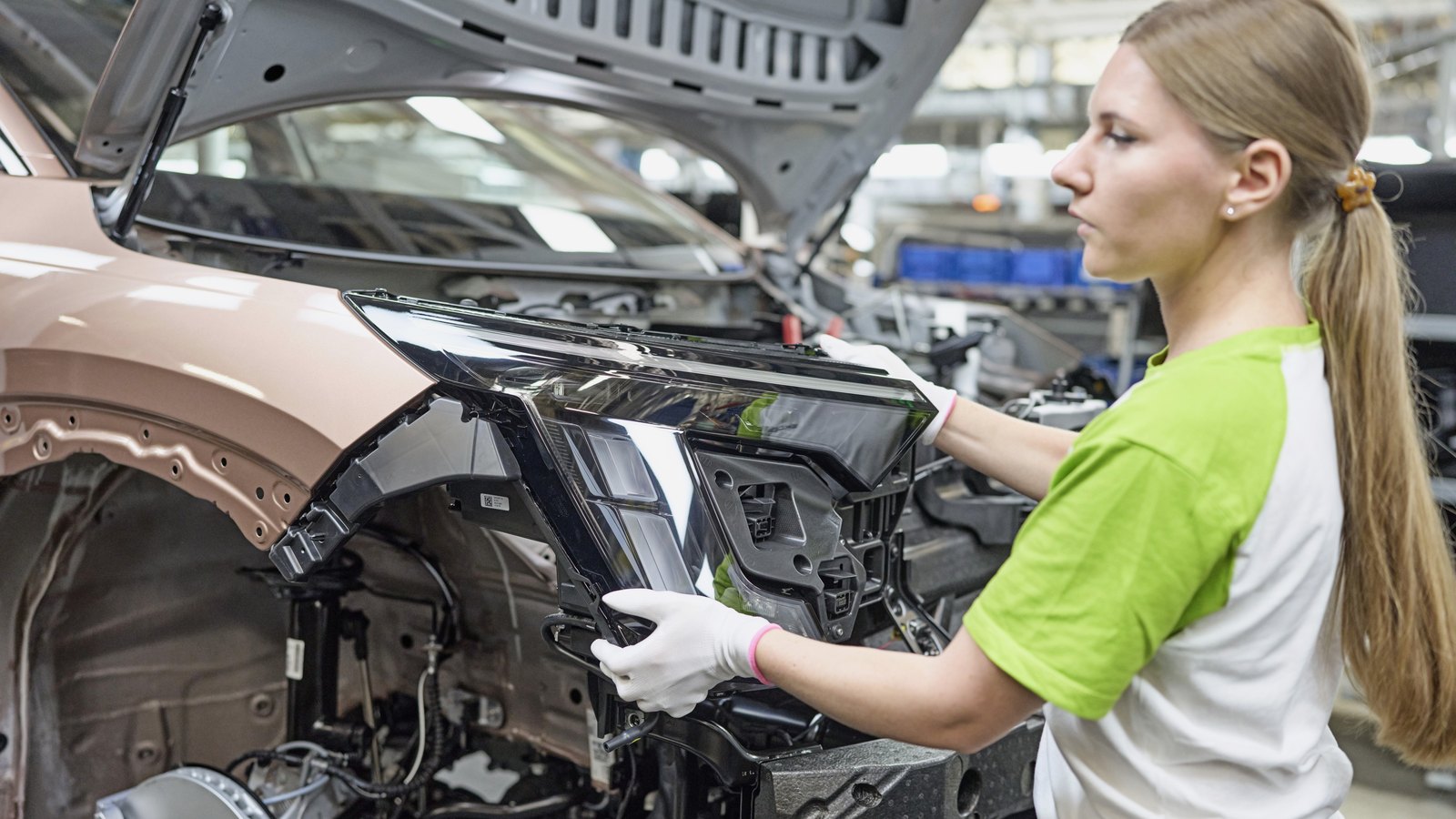 Une opératrice Škoda installe un bloc optique avant sur un Škoda Peaq en cours d'assemblage à Mladá Boleslav