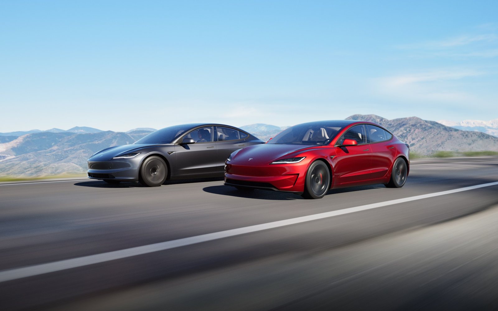Deux berlines Tesla Model 3, une grise et une rouge, roulant côte à côte sur une route de montagne