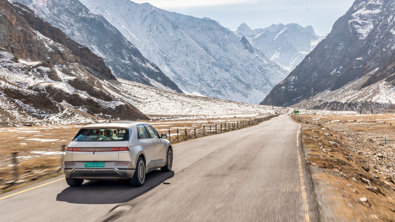Hyundai IONIQ 5 en descente sur une route de haute montagne bordée de sommets enneigés