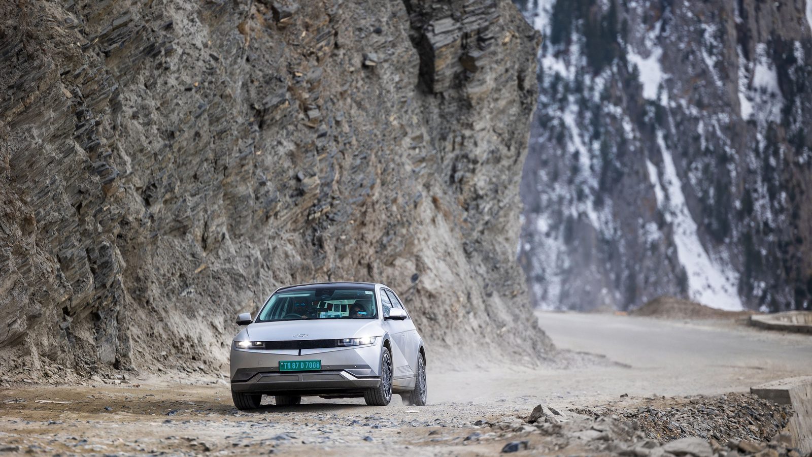 Hyundai IONIQ 5 blanche sur une route de montagne taillée dans la falaise, lors de son parcours d'altitude en Inde