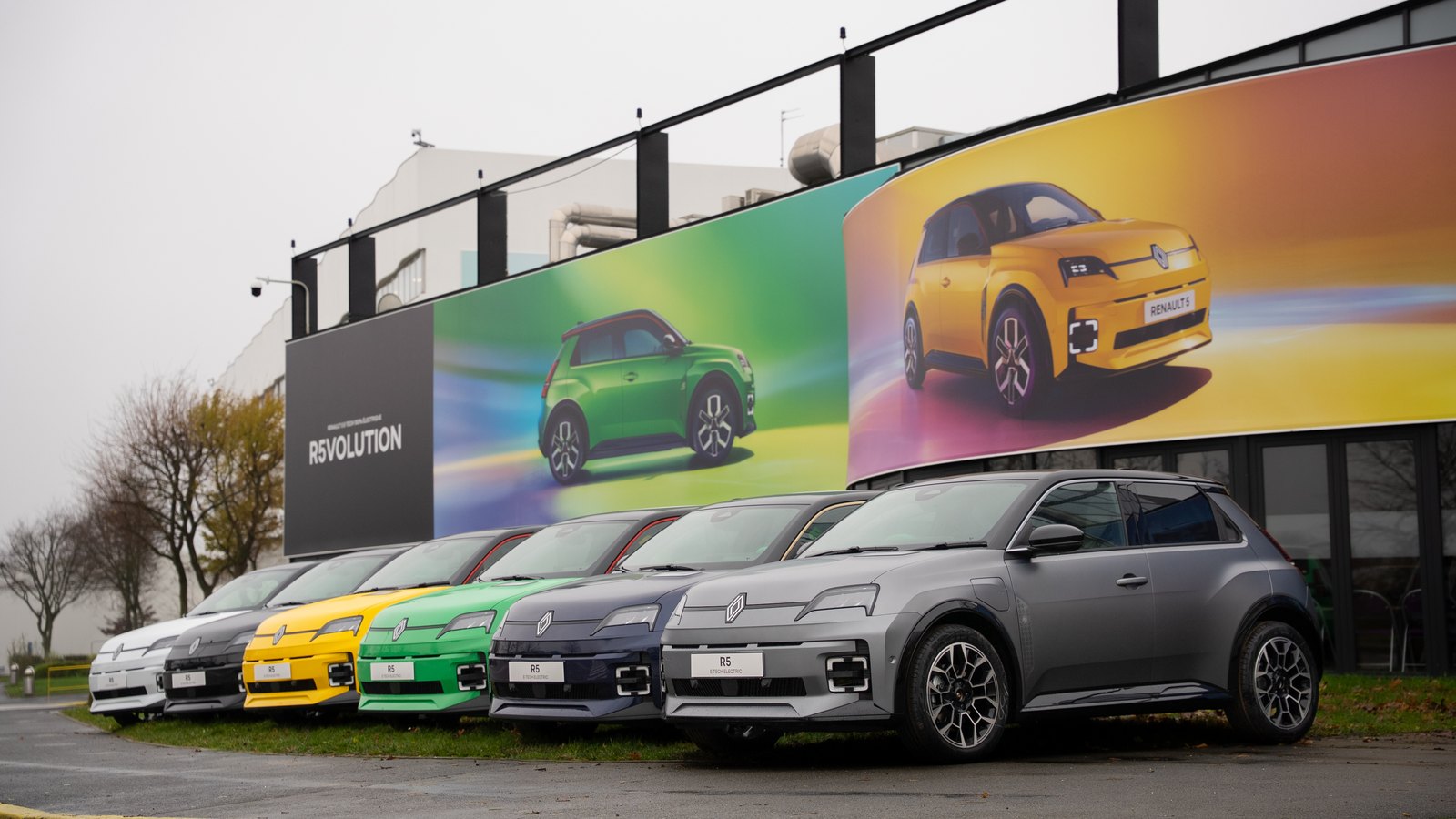 Six Renault 5 E-Tech electric de couleurs différentes alignées devant le site industriel Renault de Douai